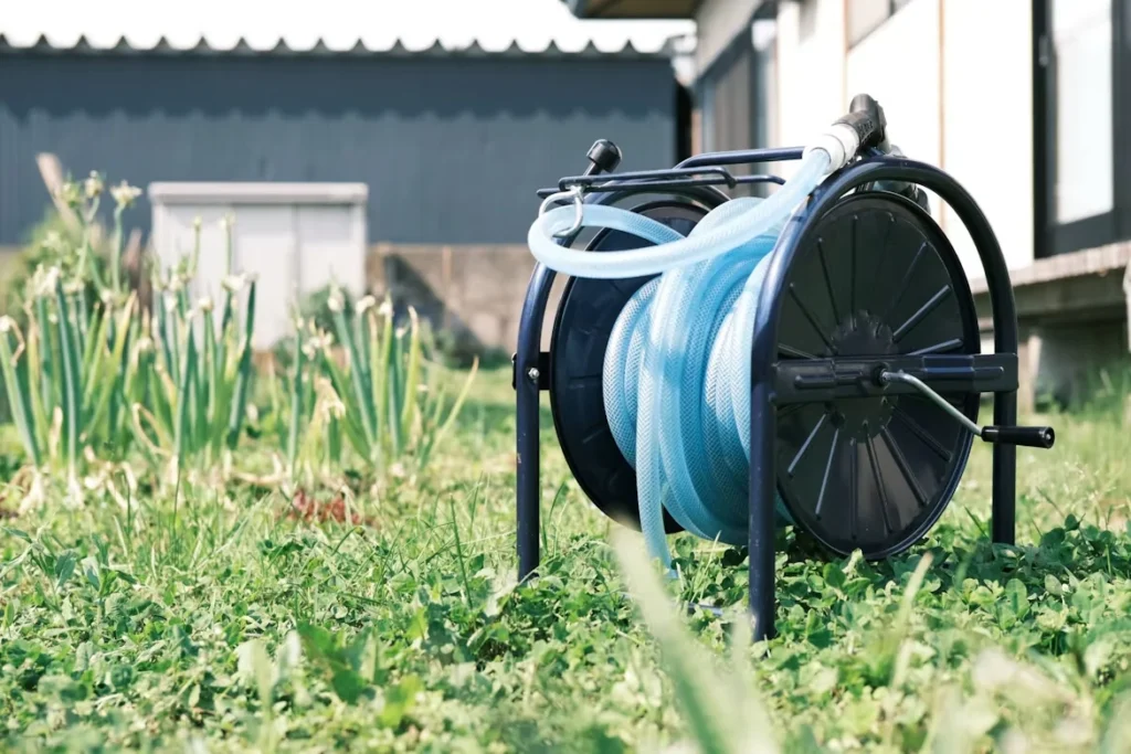Garden hose reel with coiled water hose on grass outdoors.